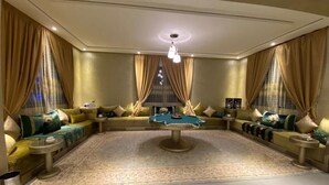 Een ruime woonkamer met een pooltafel, comfortabele zitplaatsen en een groot vloerkleed.