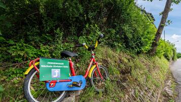 Uma bicicleta estacionada em um muro de pedra ao lado de uma estrada, com uma placa verde presa.