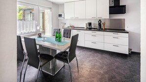 A modern kitchen with white cabinets, a dining table with chairs, and a window with a view. - Holiday Home 'Maag, 102qm' with Private Terrace and Wi-Fi (Attendorn)
