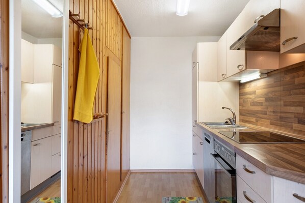 Une cuisine compacte avec des meubles en bois, un four encastré et un évier en acier inoxydable.