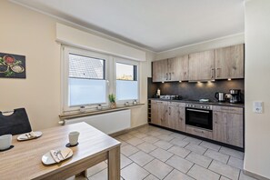 A modern kitchen with wooden cabinets, a built-in oven, and a dining area with a table set for two.