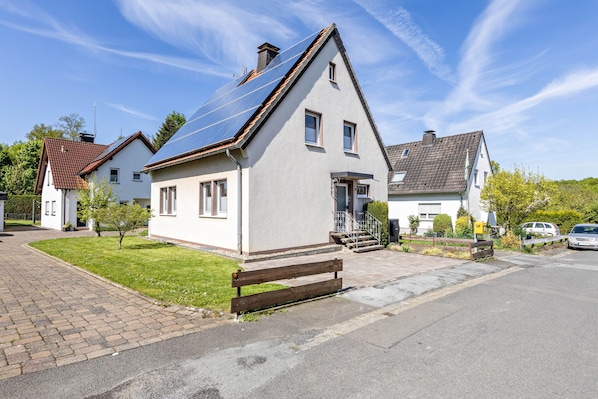 A residential house with a sloped roof, a front porch, and a small front yard.
