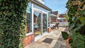 Eine Terrasse mit Glastür, Ziegelwand und Tisch mit Stühlen.