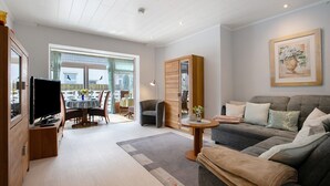 Ein modernes Wohnzimmer mit Sofa, Fernseher und Essbereich.