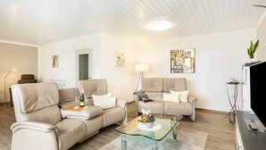 A modern living room with two beige sofas, a glass coffee table, and a flat-screen TV. - Apartment 'Landblick' with Shared Garden, Balcony and Wi-Fi (Homberg (Efze))