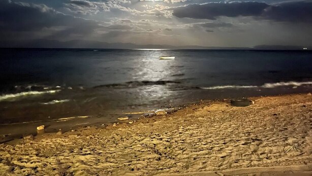 A beach at night with a calm sea, a boat on the water, and a cloudy sky. - Sea shy apartment (Dahab)