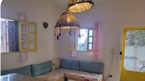 A cozy living area with a sofa, a kitchen counter, and a yellow door. - Sea shy apartment (Dahab)