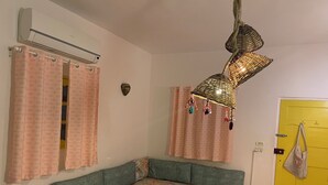 A room with a sofa, a patterned curtain, a decorative hanging light, and a yellow door. - Sea shy apartment (Dahab)