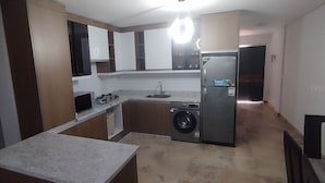 A compact kitchen with a washing machine, a refrigerator, and a sink.