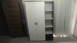 A white wardrobe with a mirrored door and a shelf unit.