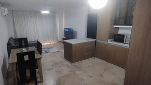 A small, compact room with a kitchenette, a single bed, and a window.