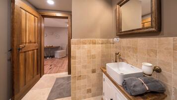 A bathroom with a wooden door, beige tiles, a white sink, and a towel on the counter.