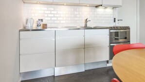 Une cuisine moderne avec des armoires blanches, un évier en acier inoxydable et un four.