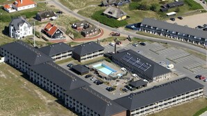 Une vue aérienne d’un hôtel comprenant plusieurs bâtiments, une piscine et un parking.