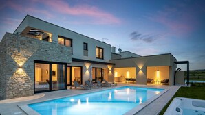 Une maison moderne à deux étages dotée d’une piscine, d’un espace salon extérieur et d’un jacuzzi.