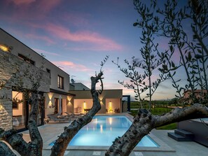 A modern house with a swimming pool, stone walls, and outdoor seating.