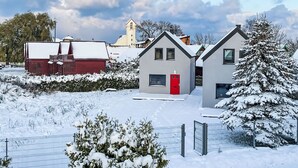 Een woonwijk met huizen, een rode deur en een kerktoren op de achtergrond.