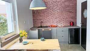 Een moderne keuken met een tegelwand, een eettafel met stoelen en een raam met uitzicht op groen.