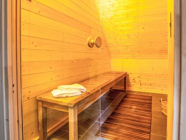 A sauna room with wooden walls, a bench, and a towel on the bench.