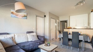 Un salon moderne comprenant un canapé, une table basse et un coin repas avec des chaises et une table.