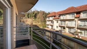 Un balcon donnant sur une rivière, un immeuble doté de nombreux balcons et un ciel dégagé.