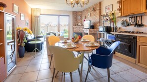 A modern kitchen with a dining area, featuring a chandelier, a brick wall, and a large window. - Geluid van de zee by Interhome (De Haan)