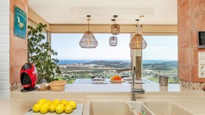 Una cocina con un amplio ventanal que da a un paisaje pintoresco, un fregadero y una encimera con limones.