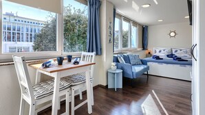 A modern room with a dining table, chairs, a sofa, and a bed.