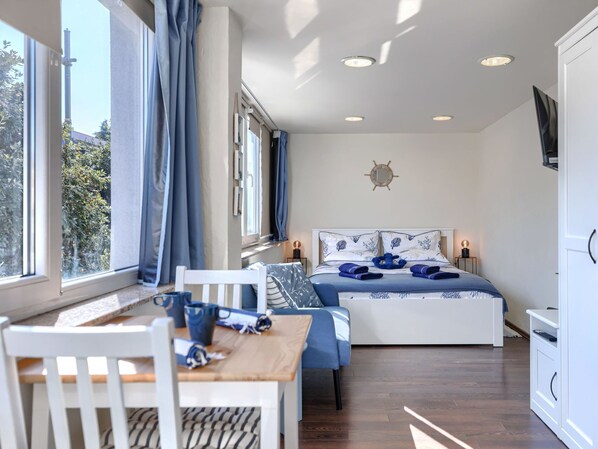 A bedroom with a bed, a desk, and a chair. There is a window with curtains, a ceiling light, and a wall-mounted TV. - Apartment Nina by Interhome (Umag)