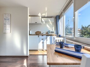 A modern kitchen with white cabinets, a wooden countertop, and a view of the city through large windows. - Apartment Nina by Interhome (Umag)