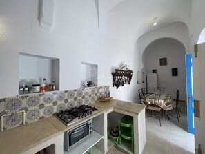 Compact kitchen with gas stove and oven, adjacent dining area with table and chairs.