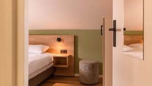 A bedroom with a bed, bedside table, and a small stool. - Bungalow in Reevallis near Scenic Hills (Vijlen)