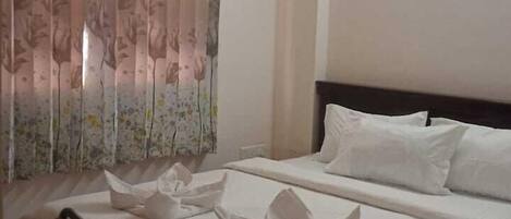 A hotel room with a bed, a desk, and a ceiling fan.