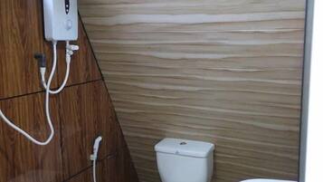 A small bathroom with a toilet, bidet, and a wall-mounted hand dryer.