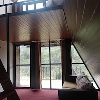 Una habitación con techo alto, ventanas amplias y alfombra roja.