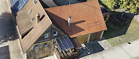 Un bâtiment doté d’un toit en pente, de panneaux solaires et d’une petite structure adjacente recouverte de tuiles.