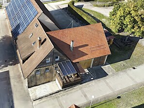 A building with a sloped roof, solar panels, and a small attached structure with a tiled roof.