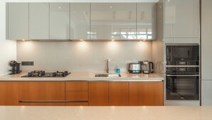 Een moderne keuken met een roestvrijstalen afzuigkap, een ingebouwde oven en een dubbele spoelbak.