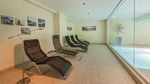 Uma área de espera com cadeiras reclináveis, um abajur e obras de arte nas paredes.