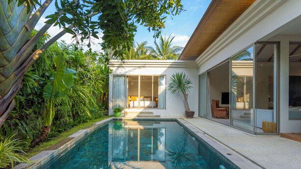 A modern house with a swimming pool, surrounded by lush greenery and a well-maintained garden. - Famous 5 Trichada Resort  4-Bedroom V164 (Choeng Thale)