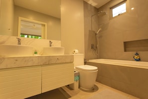 Un baño moderno con dos lavamanos, un inodoro y una bañera.