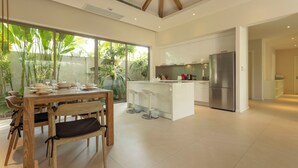 A modern kitchen with a central island, white cabinetry, and a stainless steel refrigerator. - Famous 5 Trichada Resort  4-Bedroom V164 (Choeng Thale)