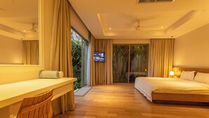 A modern hotel room with a wooden desk, a bed with white linens, and a television on the wall. - Famous 5 Trichada Resort  4-Bedroom V164 (Choeng Thale)