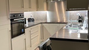 A modern kitchen with stainless steel appliances, beige cabinetry, and a black countertop. - Victorian terrace house (Edinburgh)