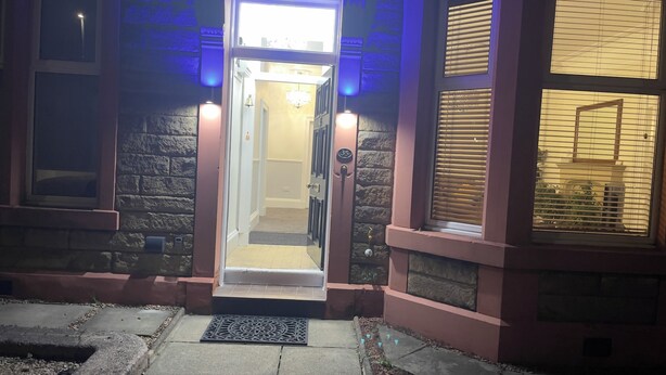 A building entrance with a door leading to a hallway, a stone wall, and a window with blinds. - Victorian terrace house (Edinburgh)