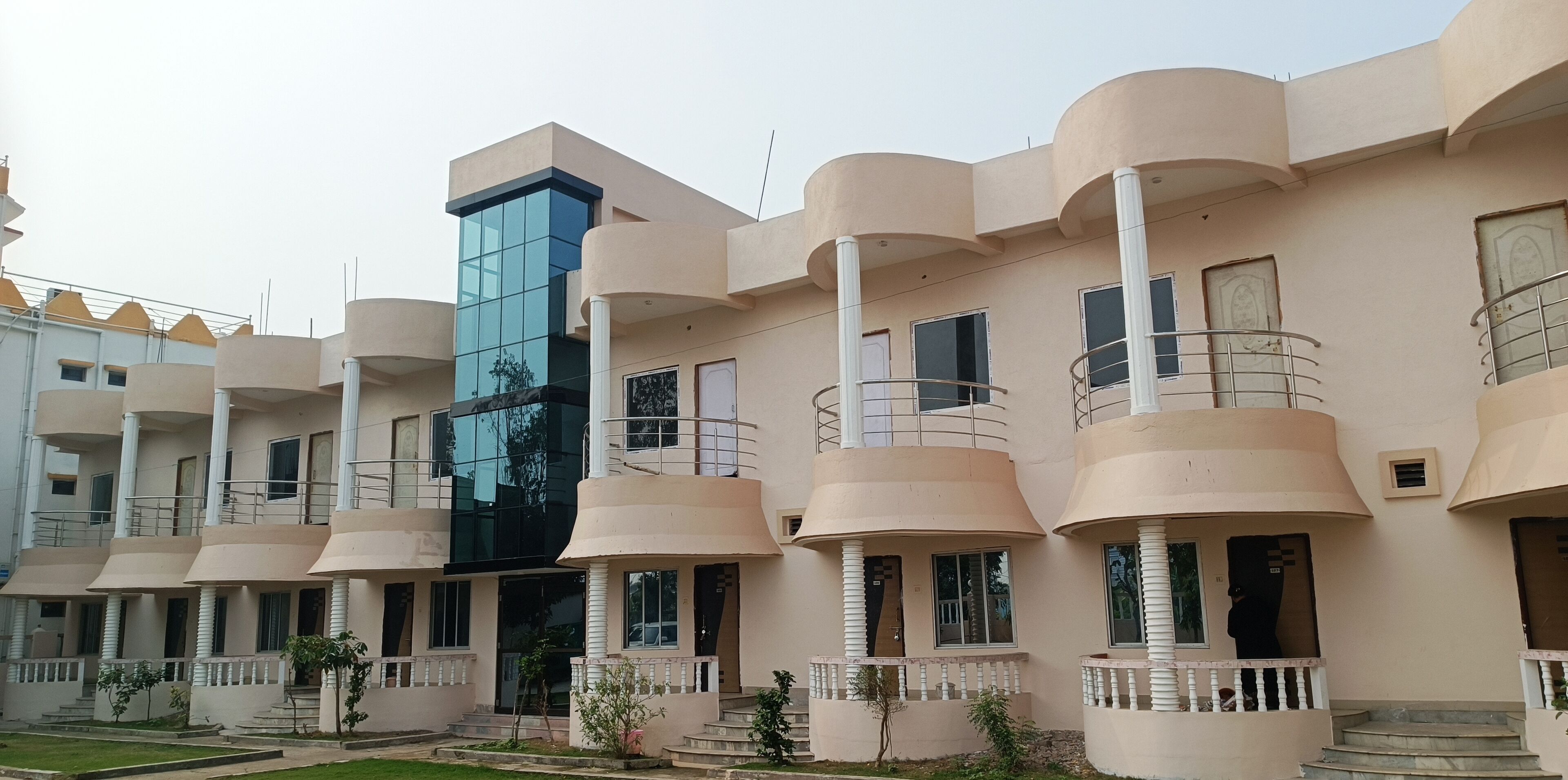 A multi-story building with a modern architectural design, featuring balconies with railings and a central glass facade.