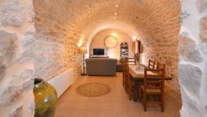 A stone-walled interior with a sofa, dining table, chairs, and a television. - Rafal baix - idyllic country house with private pool (Son Servera)