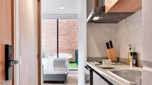 Cozinha moderna com máquina de lavar louça embutida, pia e janela com vista para uma parede de tijolos.