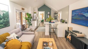 A modern open-plan living and dining area with a kitchen, large windows, and a view of the outdoors.