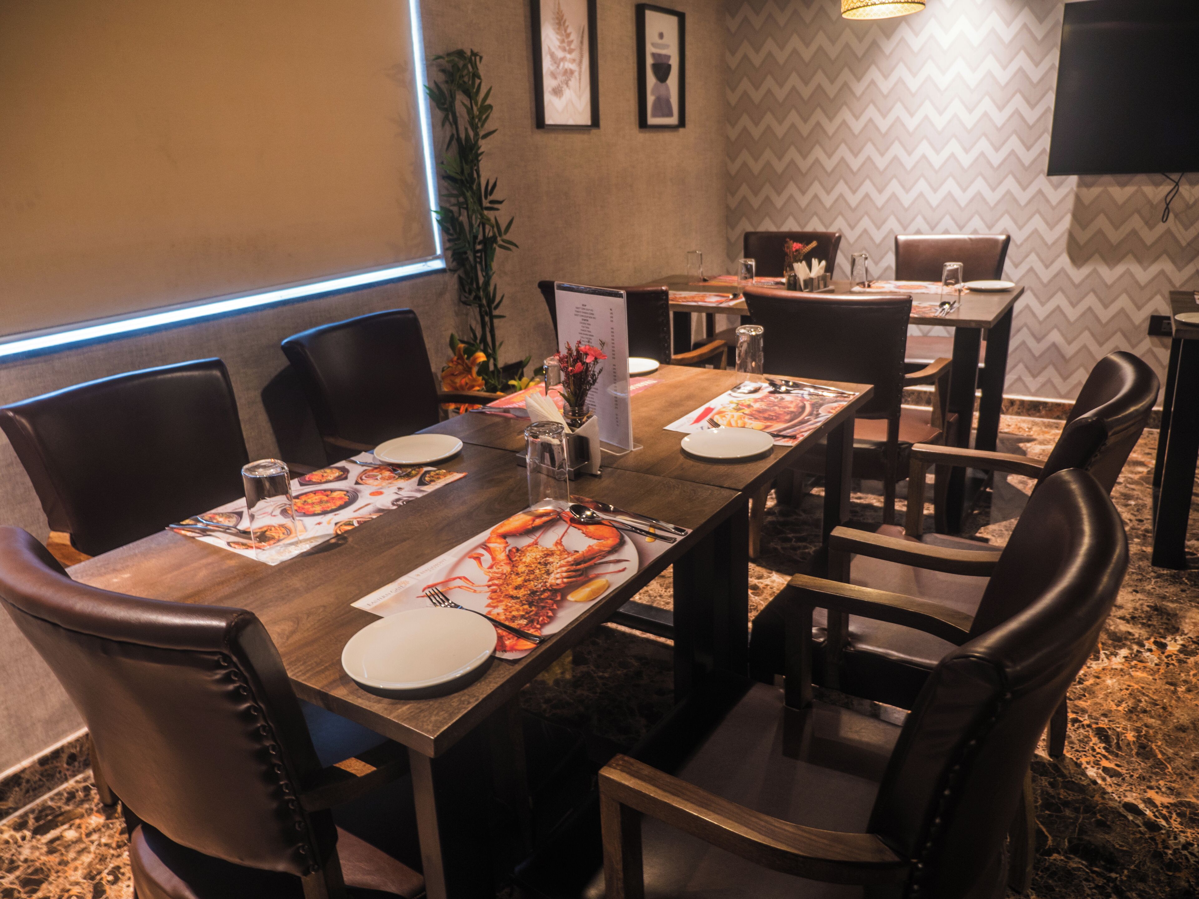 A conference room with a long table, chairs, a projector screen, and framed artwork on the wall.
